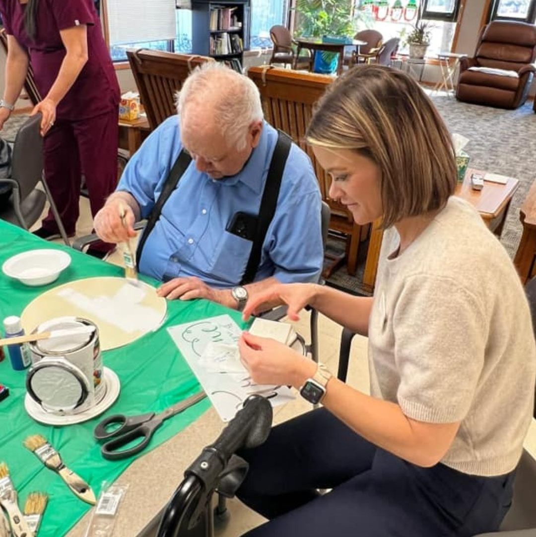 Residents engaging in a painting activity with staff assistance