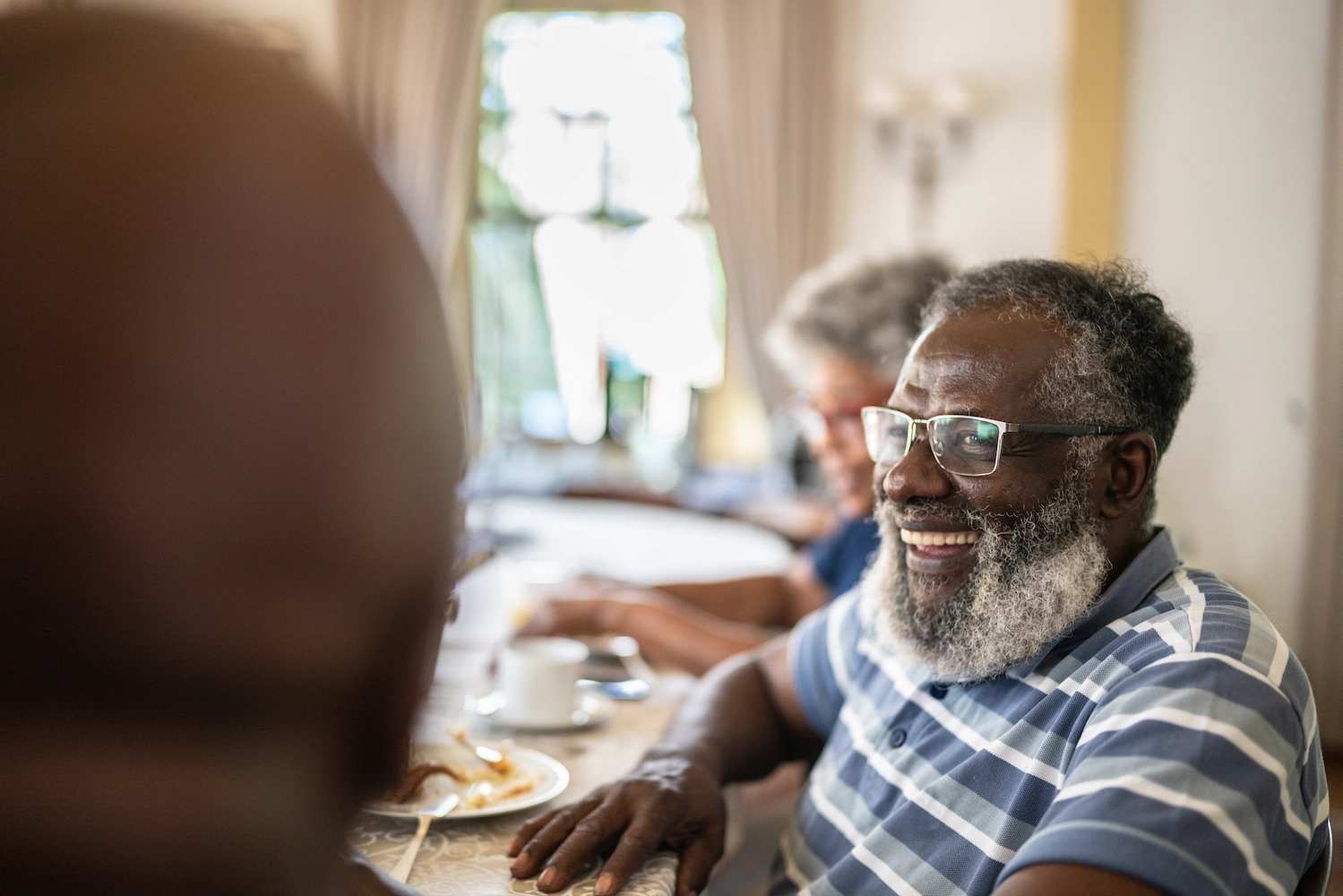 A smiling resident with a beard enjoying time indoors