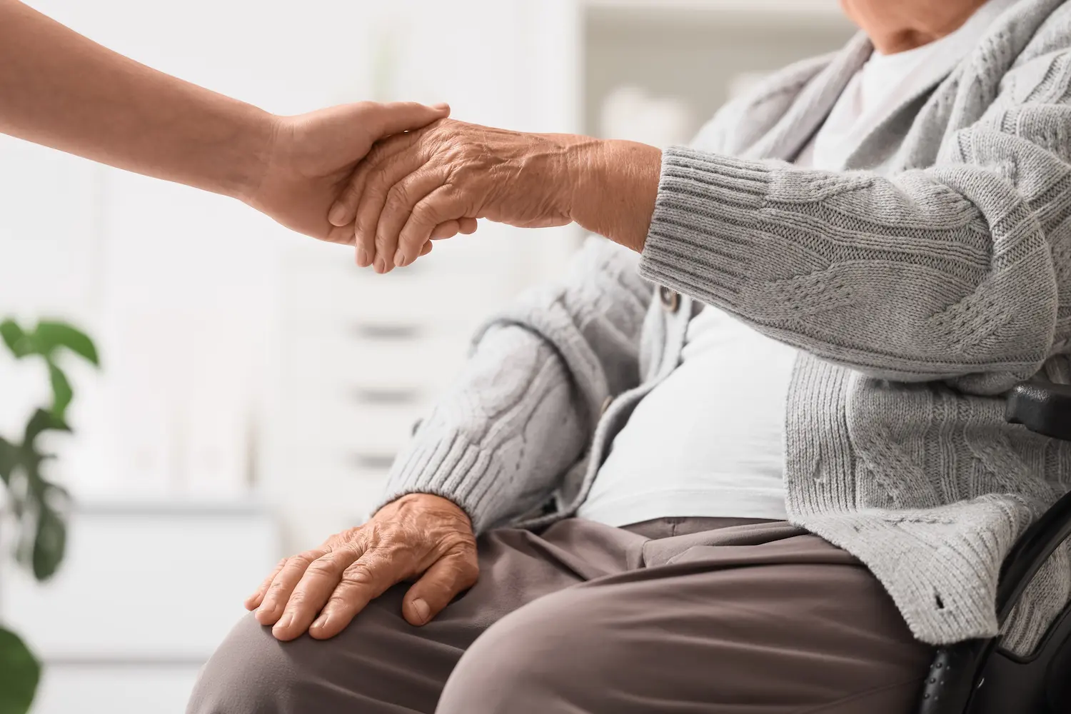 A caregiver holding the hand of a senior resident