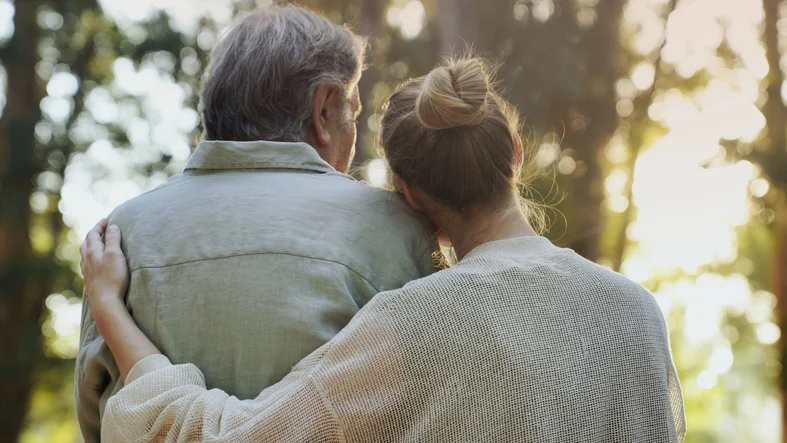 A caregiver embracing a senior in a natural setting