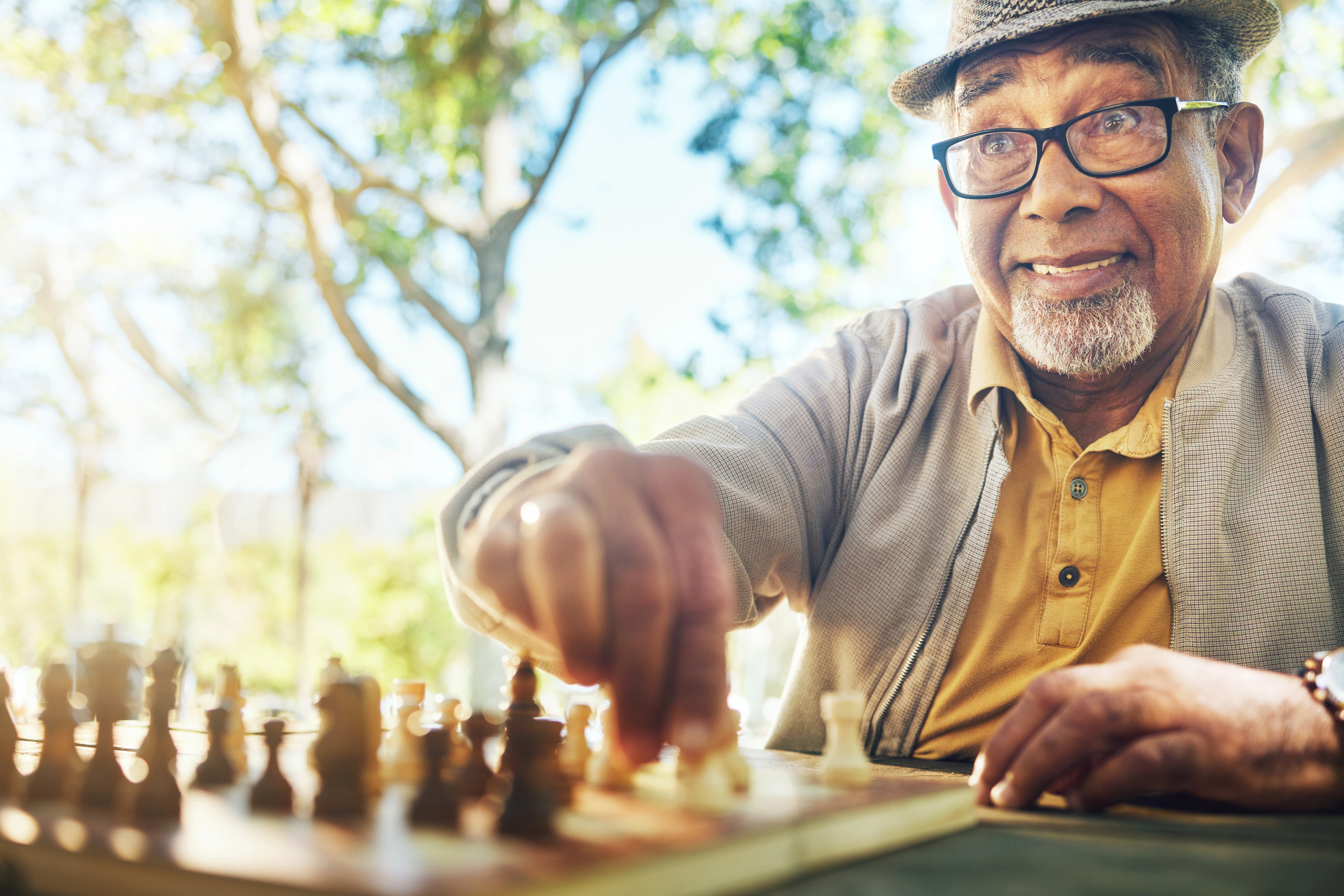 Senior man playing chess outdoors in a garden