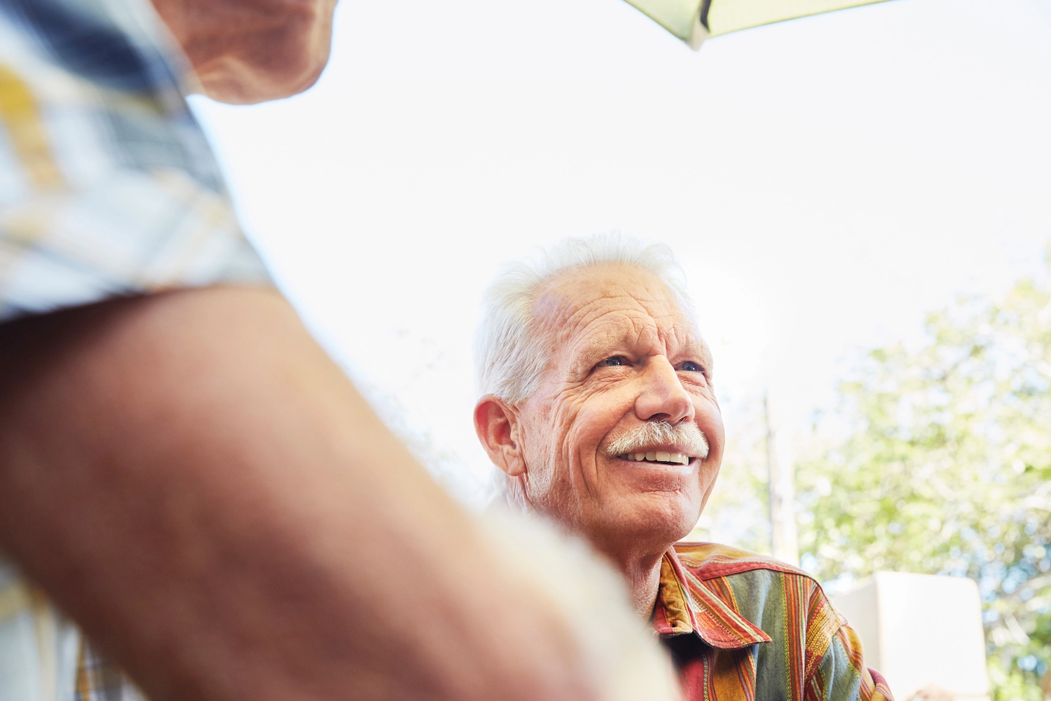 A smiling elderly man enjoying an outdoor chat