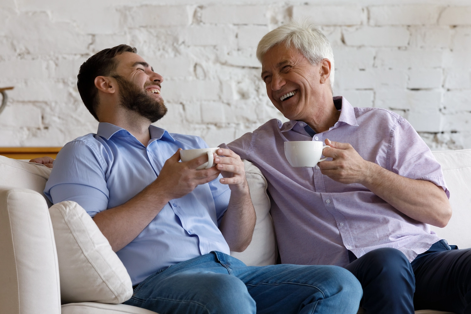 Two men enjoying coffee and laughing in a common area