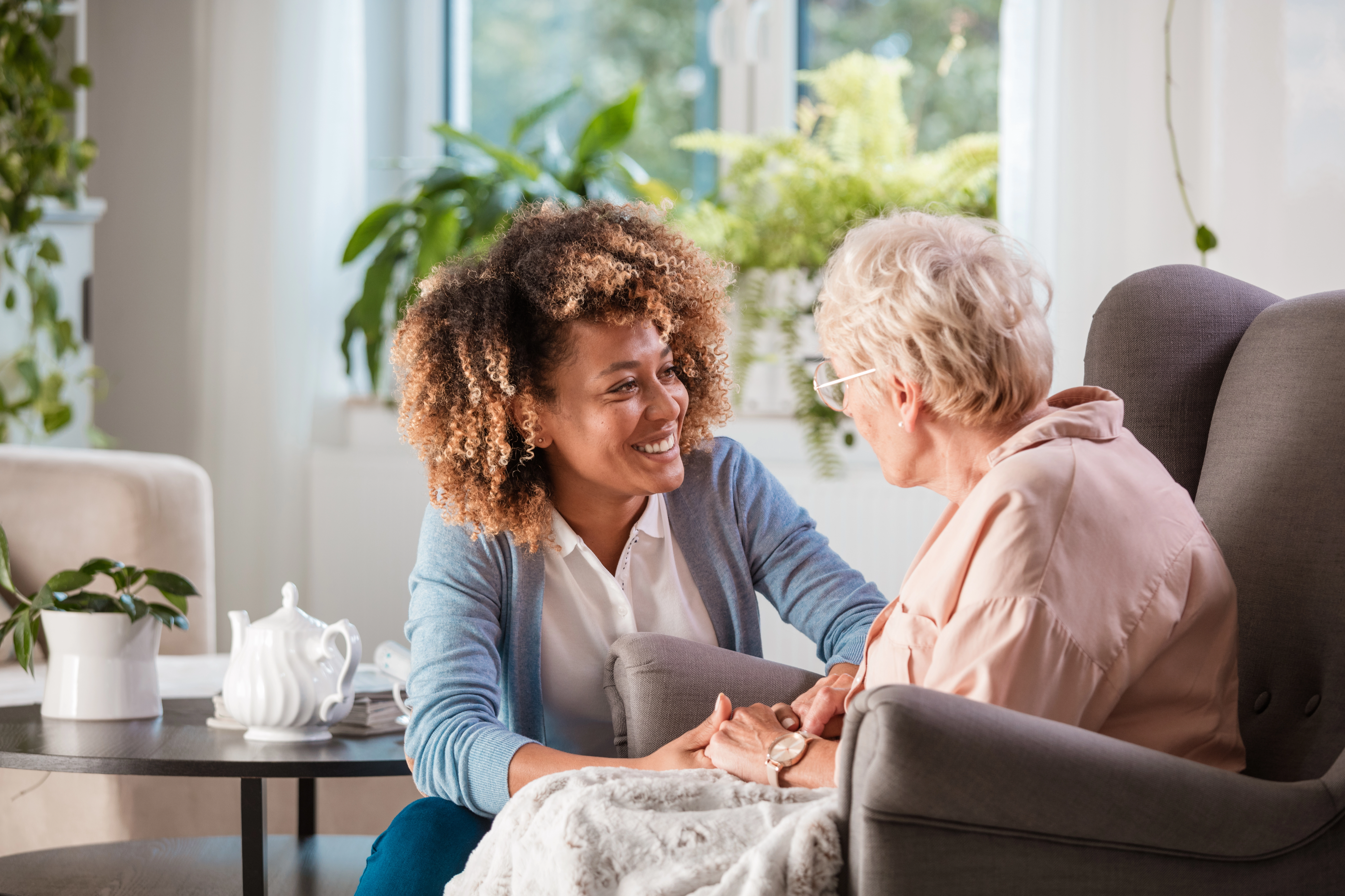A caregiver interacting with an elderly resident in a cozy lounge