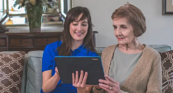 Staff member assisting a resident with a tablet