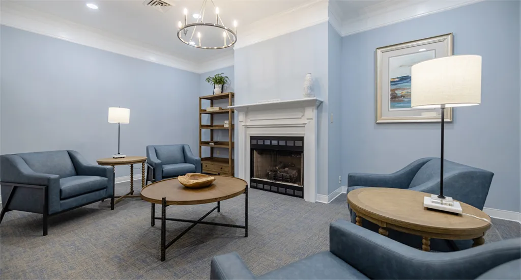 A cozy common area with blue chairs and a fireplace