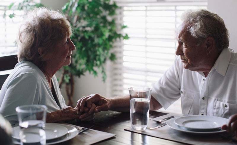 Two residents holding hands at a dining table