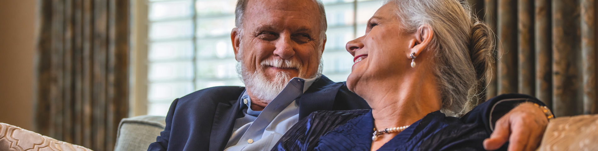 Couple smiling together on a sofa in a cozy room