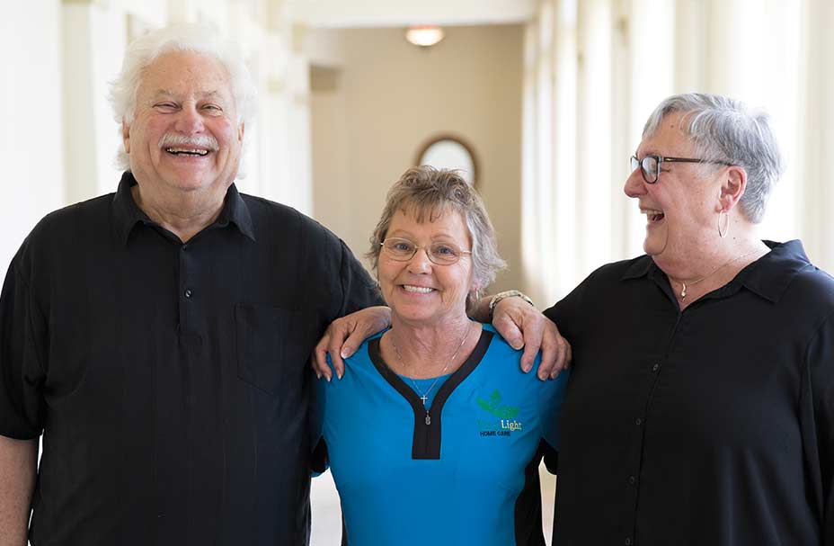 Two residents and a caregiver smiling together
