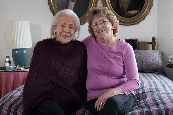 Two women smiling together in a bedroom