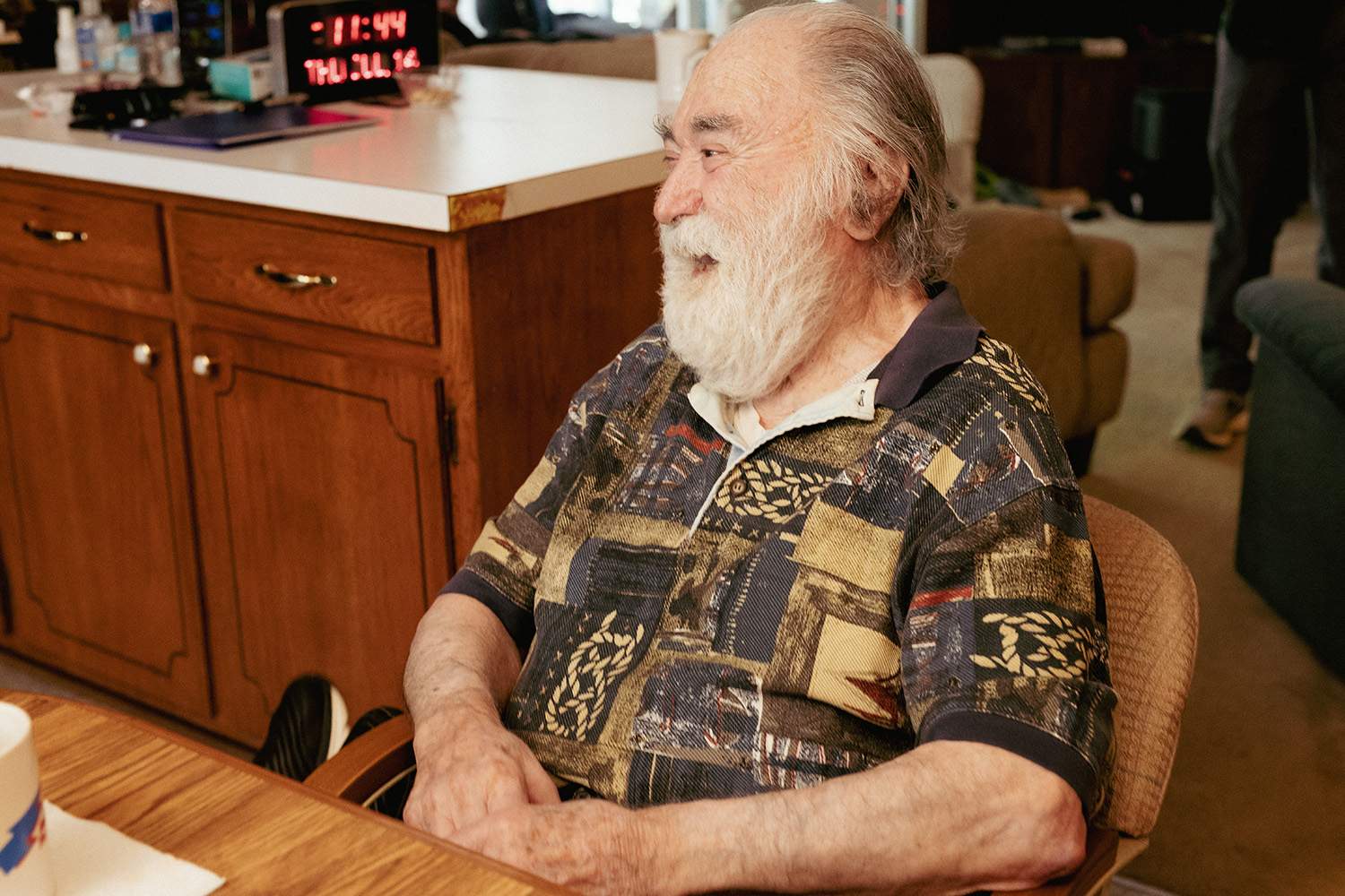 Older man with a beard smiling at a table