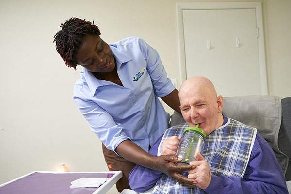 Caregiver assisting a senior with a drink
