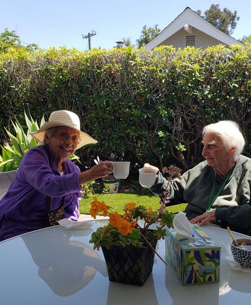 Residents enjoying tea in a garden setting.