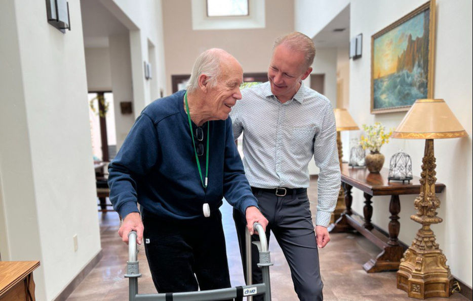 Senior resident using walker with staff assistance