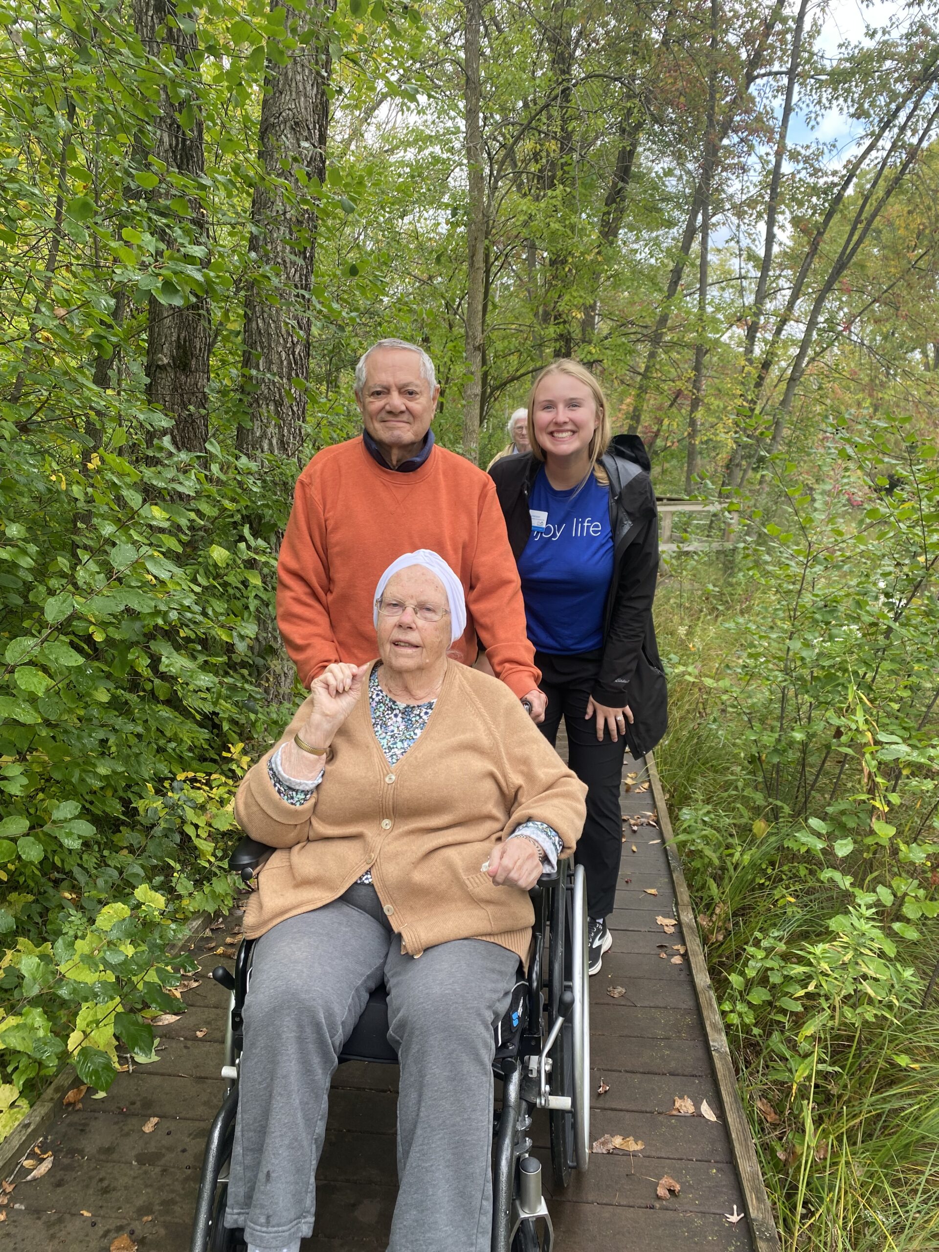 Three individuals outdoors near trees