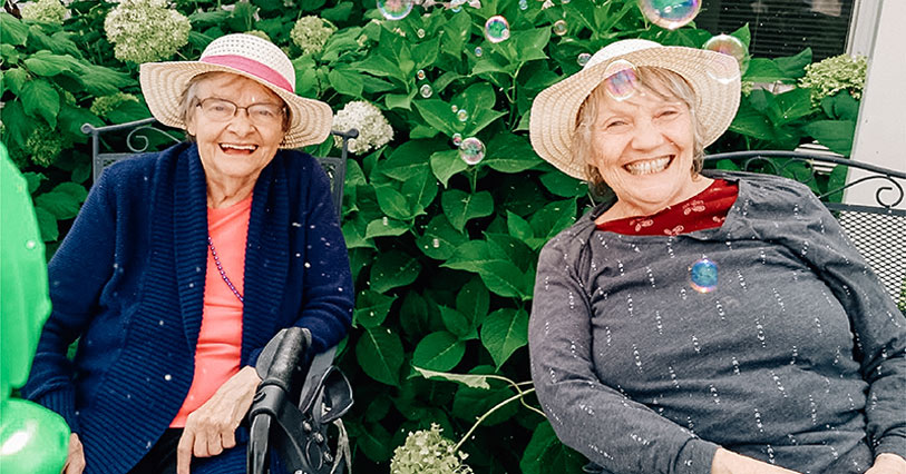 Two seniors smiling outdoors with hats
