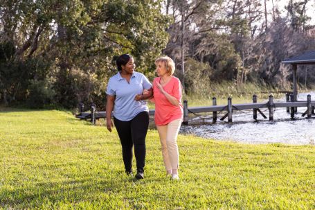 Caregiver and resident walking by a waterfront