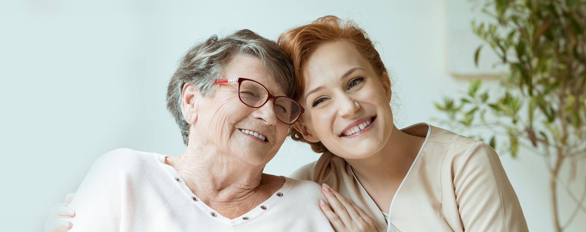 Smiling senior woman with caregiver in indoor setting.