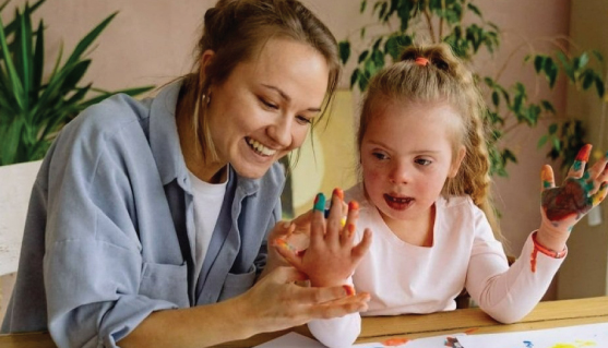 A caregiver and child painting together.
