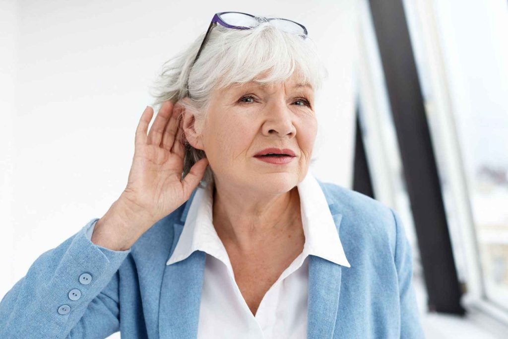 Elderly woman listening attentively indoors.
