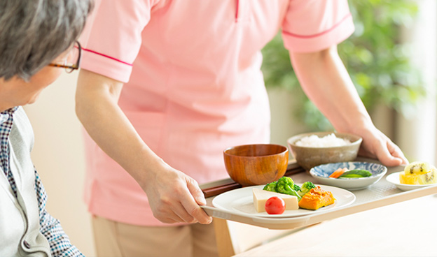 Caregiver serving a meal to an elderly resident