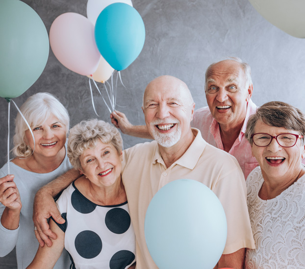 Group of smiling seniors celebrating with balloons