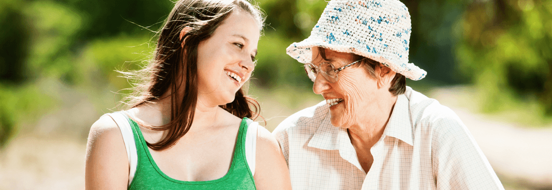 A senior woman enjoying time with a younger companion outdoors.