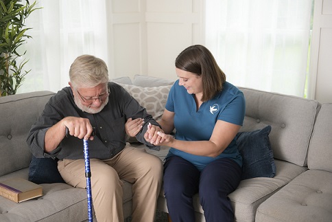 Caregiver assisting senior man on a couch
