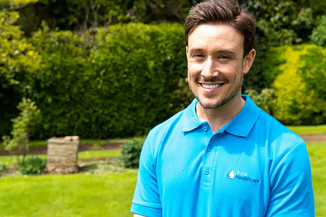 Smiling staff member in a garden setting.