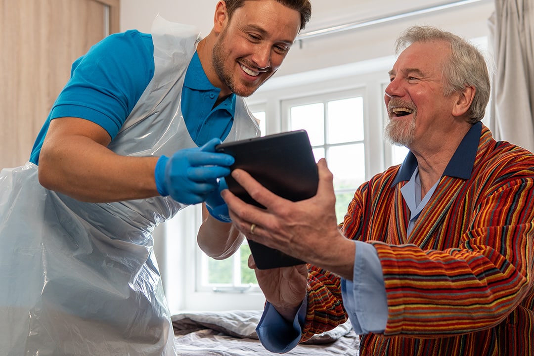 Care staff engaging with a resident over a tablet.