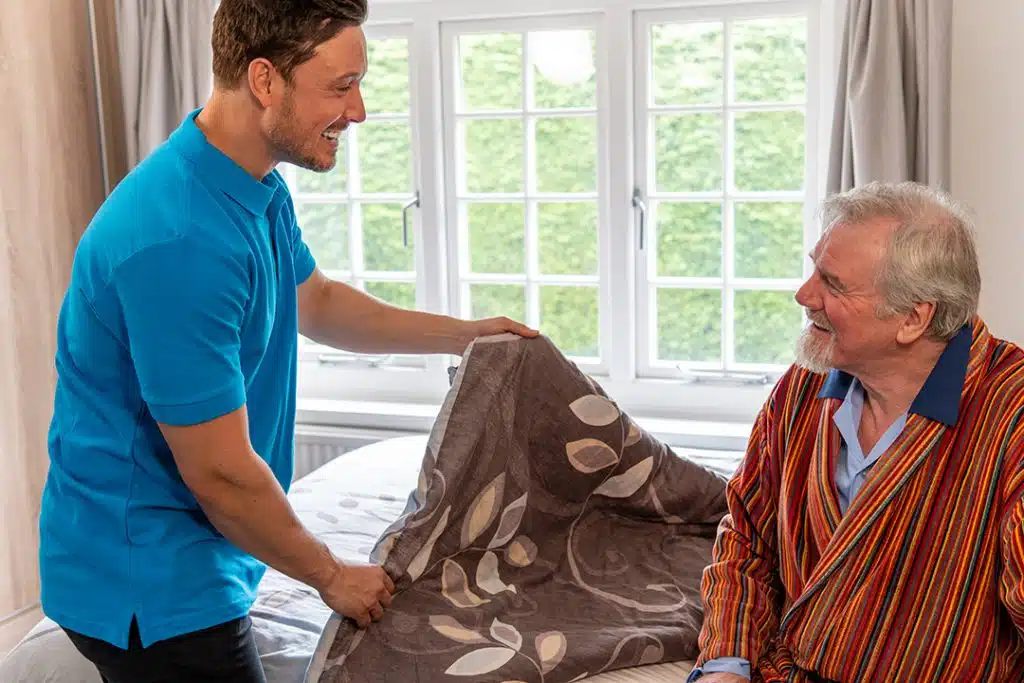 Caregiver assisting a senior resident in a room.