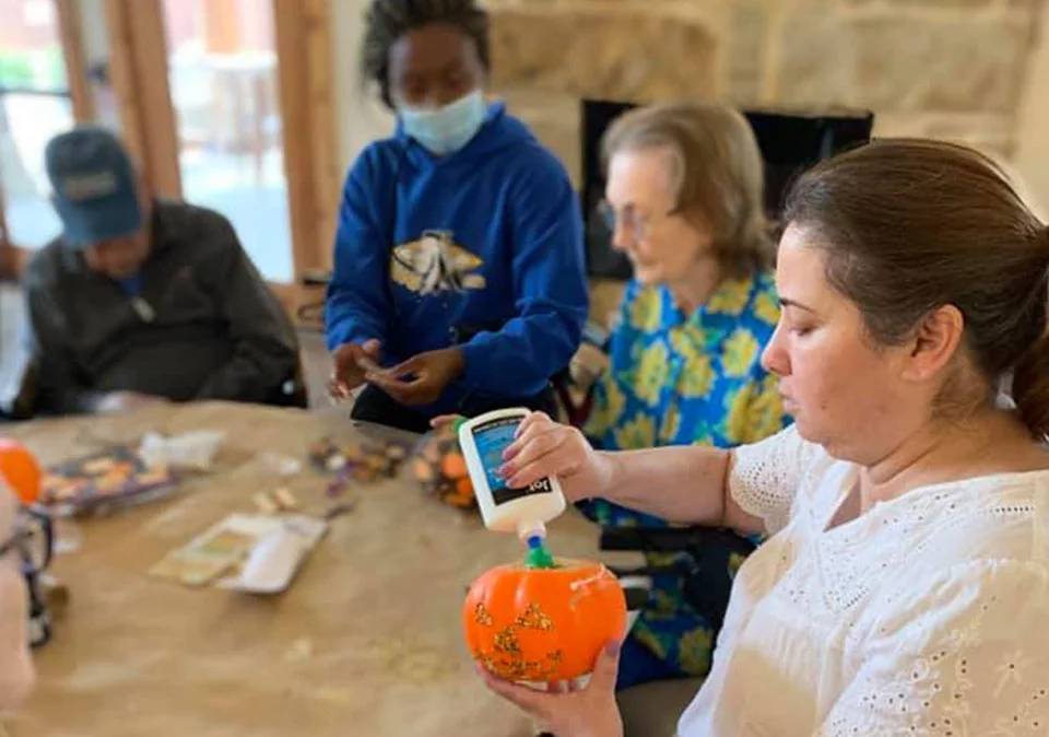 Residents engage in a pumpkin decorating activity.