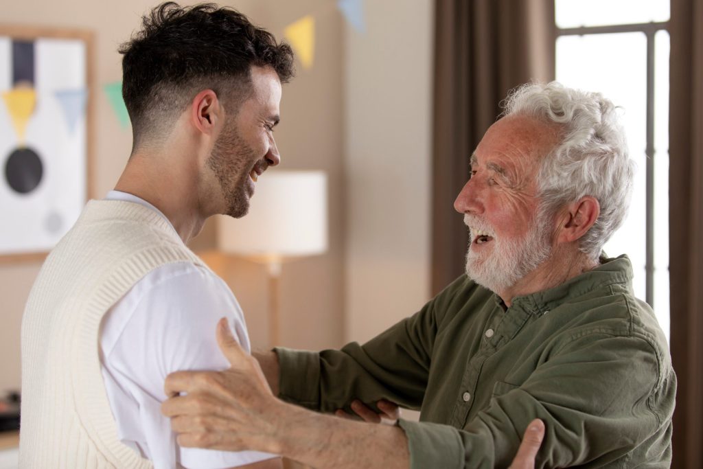 A caregiver and a senior resident smiling and embracing.