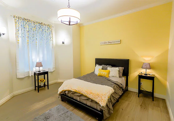Cozy bedroom with yellow walls and decorative elements.