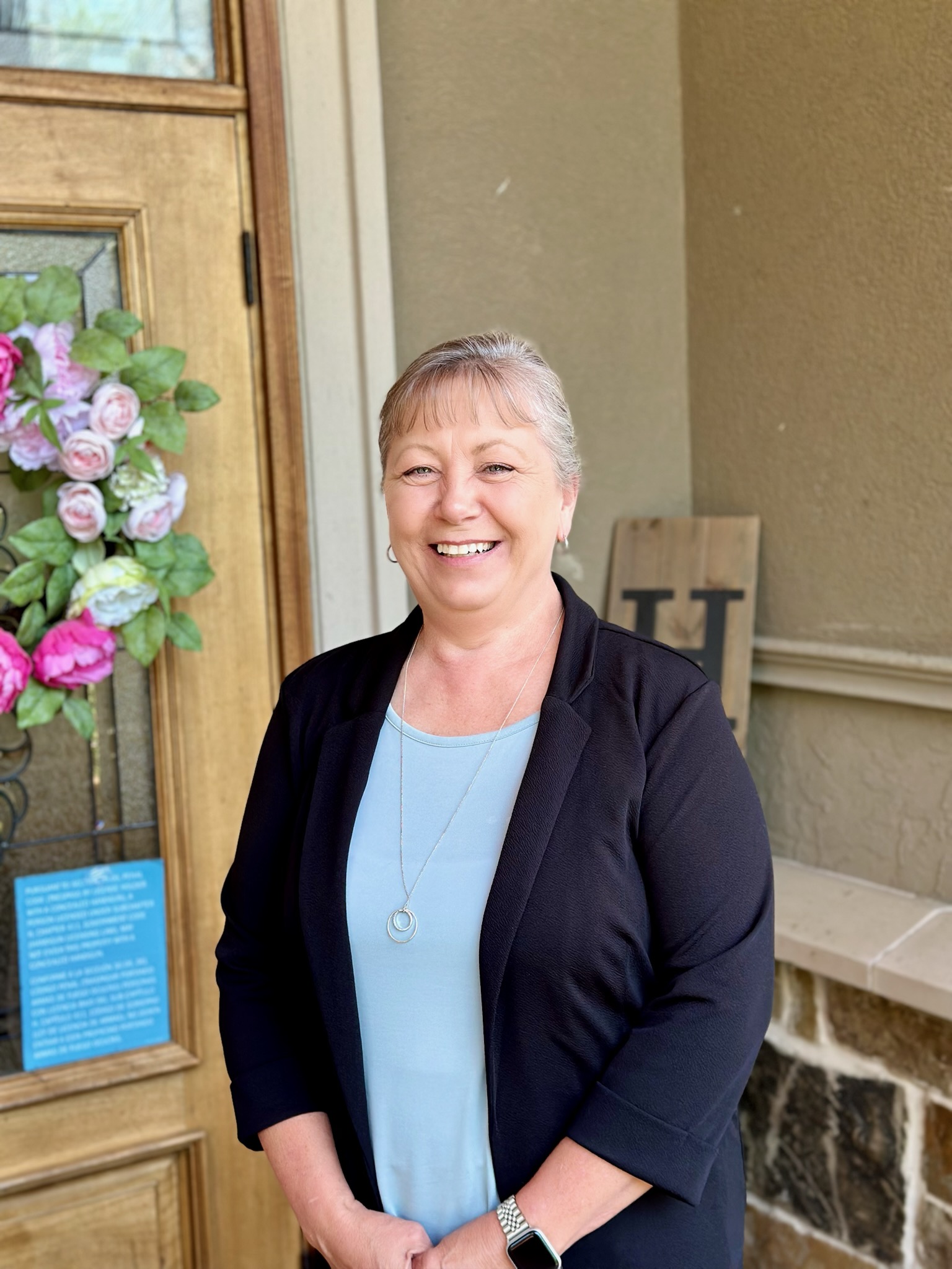 Smiling staff member standing by the entrance door.