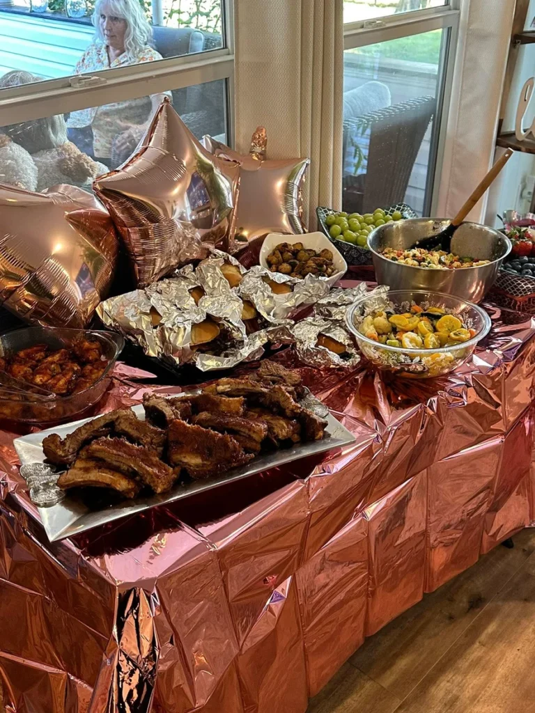 A dining setup with a variety of food and a resident in the background