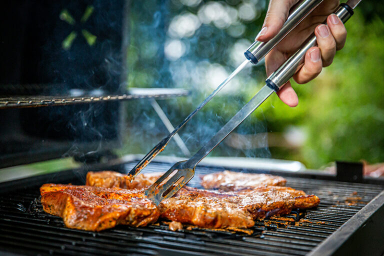 Grilling steaks outdoors in a garden setting