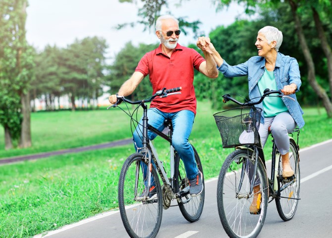 Two seniors riding bicycles in a park