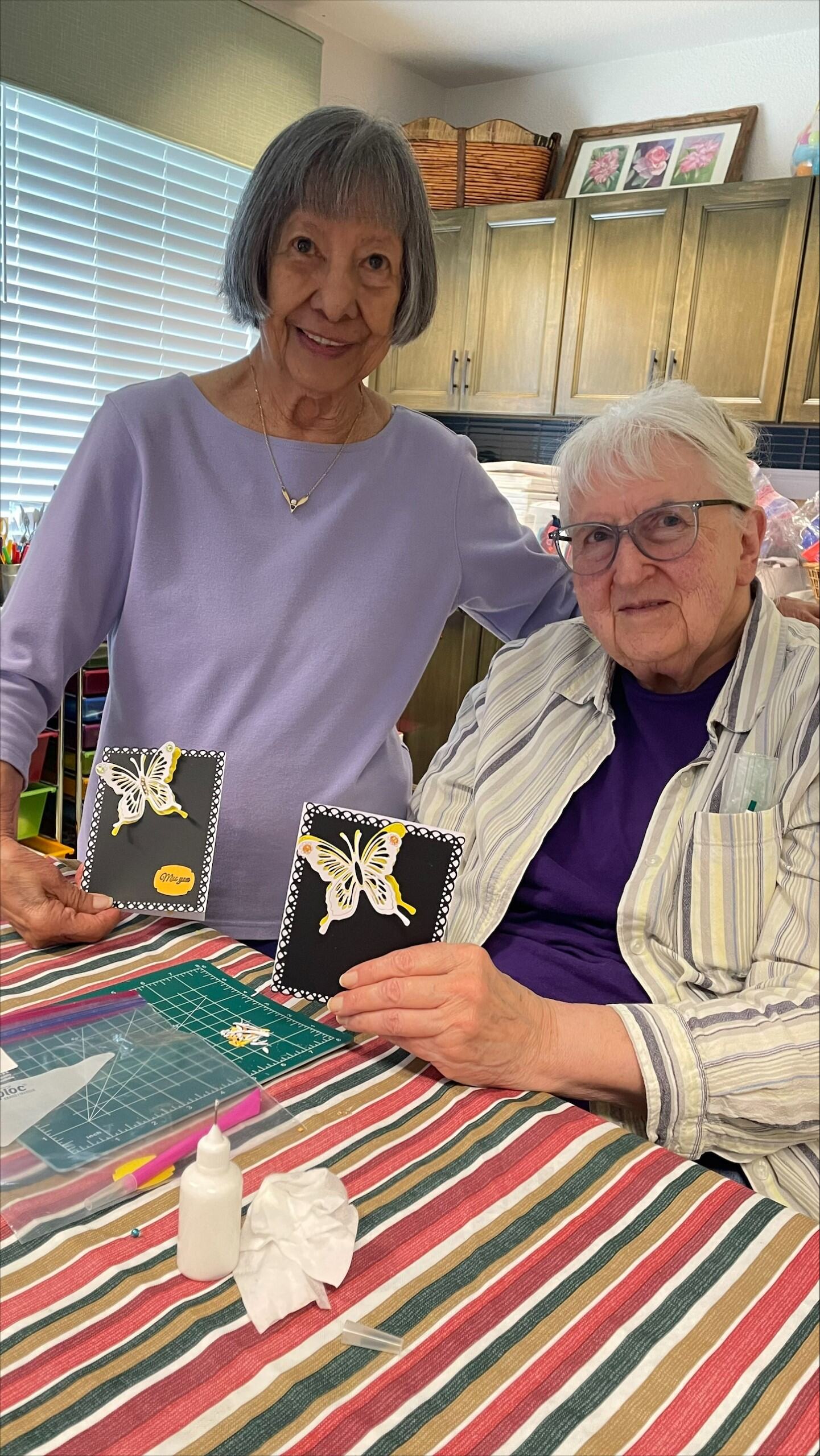 Two residents holding handmade cards in a communal space