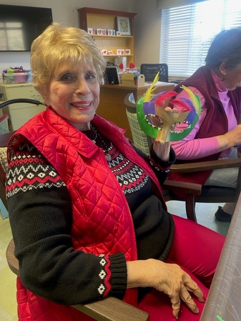 A resident holding a colorful craft project in an activity room