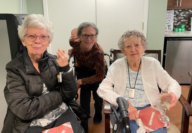 Two residents sitting together with staff member behind
