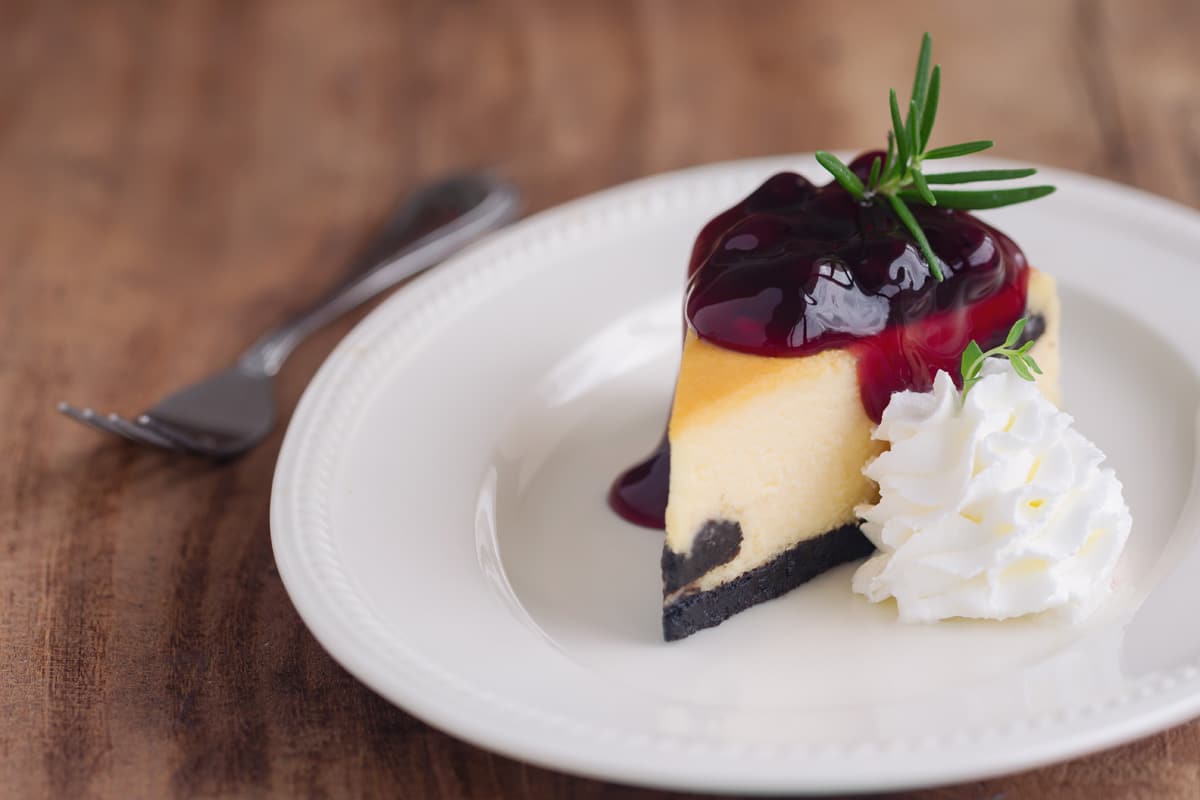 A slice of cheesecake with berry topping and whipped cream