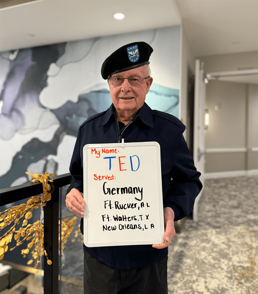 Resident named Ted holding a sign about his service in Germany