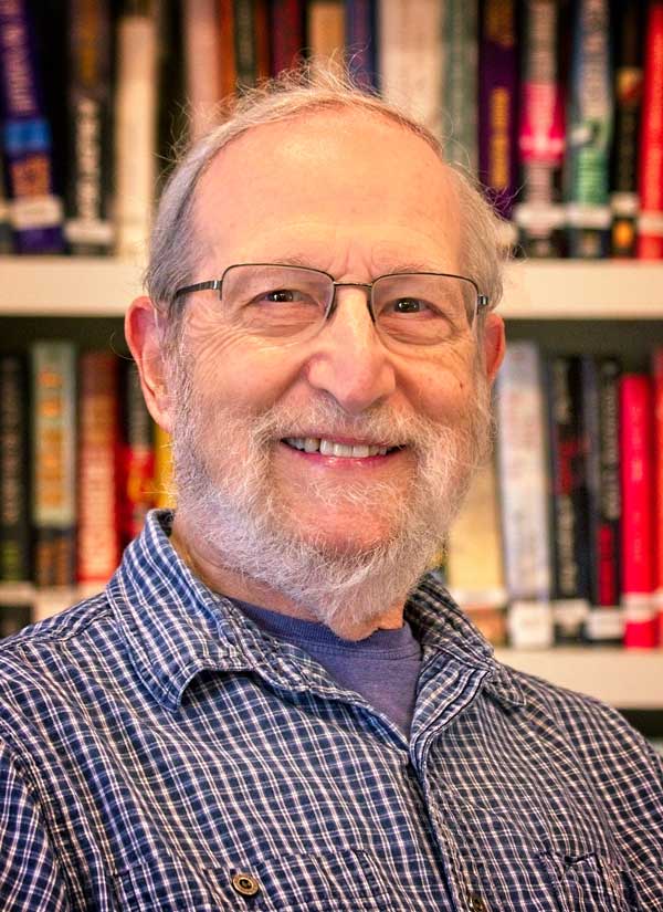 A smiling elderly man in a library setting