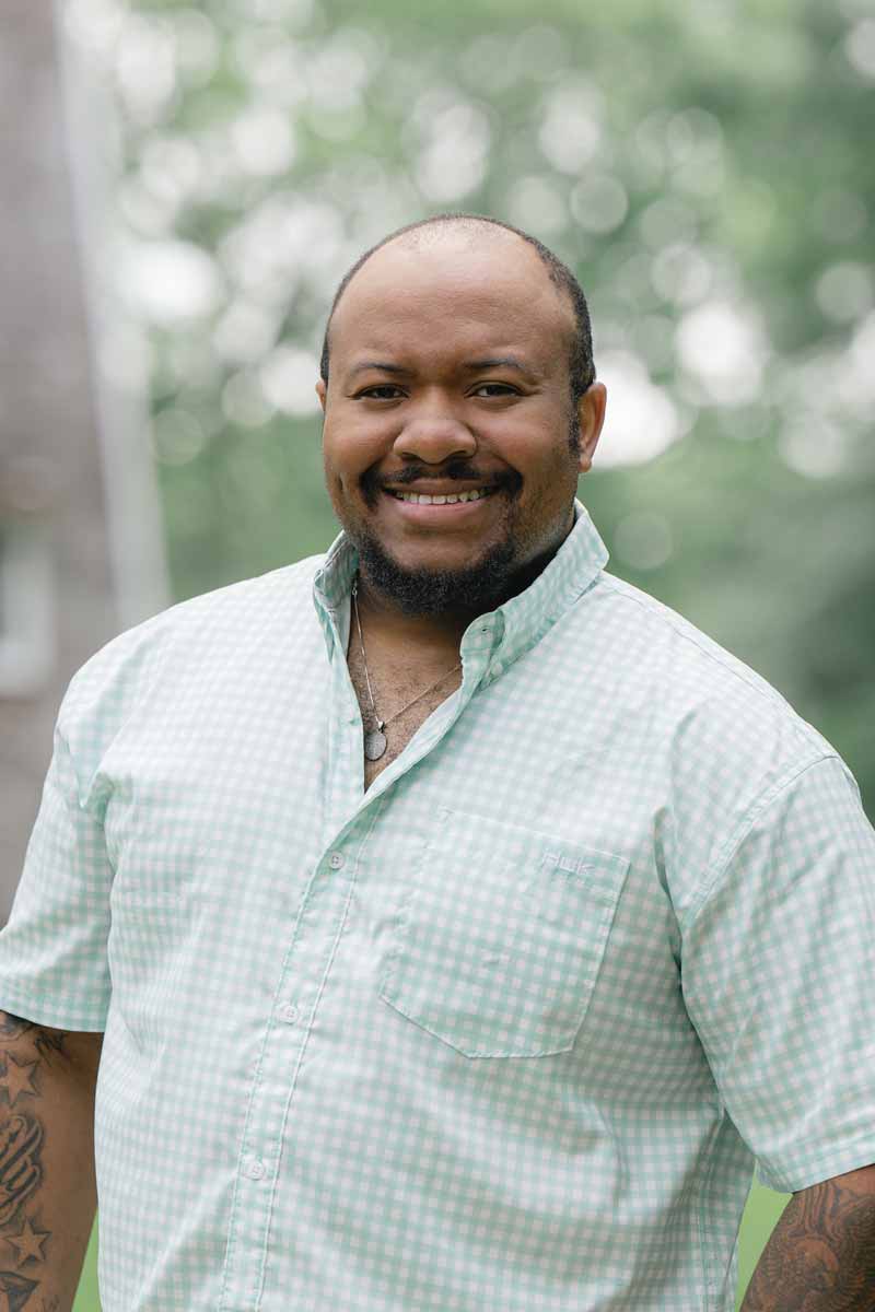 Smiling staff member outdoors in a green setting