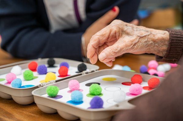 Residents engaging in a colorful activity with pom-poms