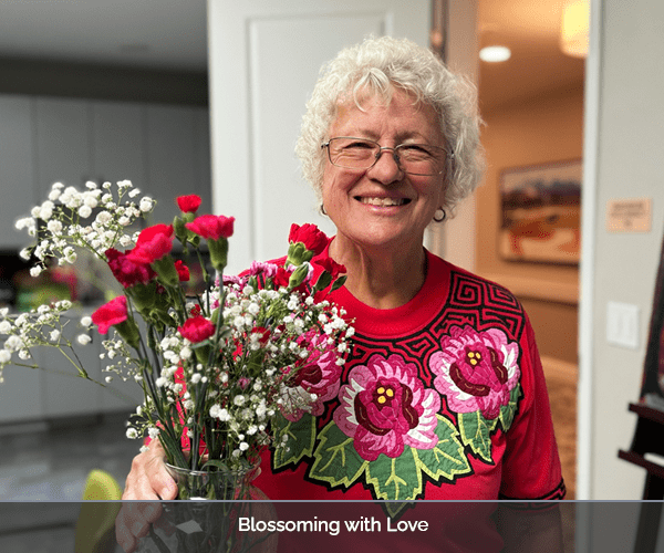 Resident smiling and holding a flower bouquet