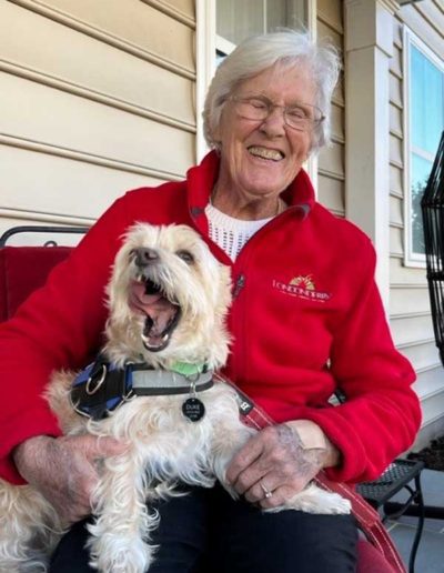 A smiling resident with a dog on a porch