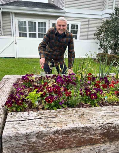 A resident tending to colorful flowers in a garden
