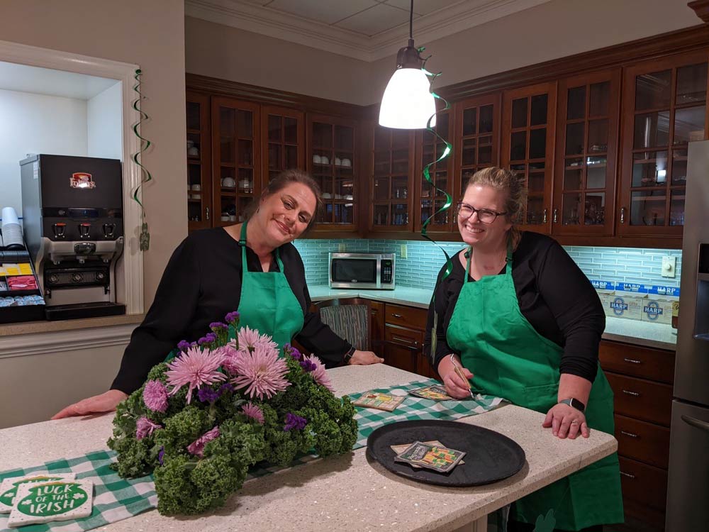 Two staff members smiling in a kitchen setting